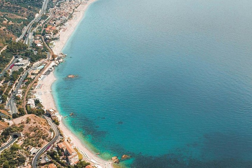 A coastal area with a beach, a road, and a clear blue sea. 3