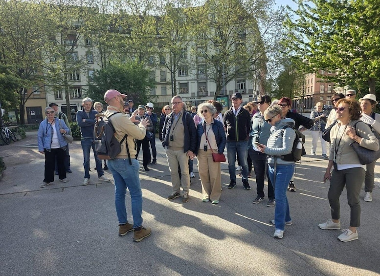A group of people gathered outdoors, some taking photos, with buildings and trees in the background. 5