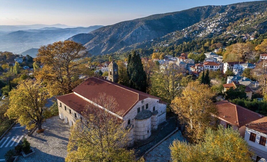 A mountainous town with a prominent church, autumn foliage, and a clear view of the valley below. 1