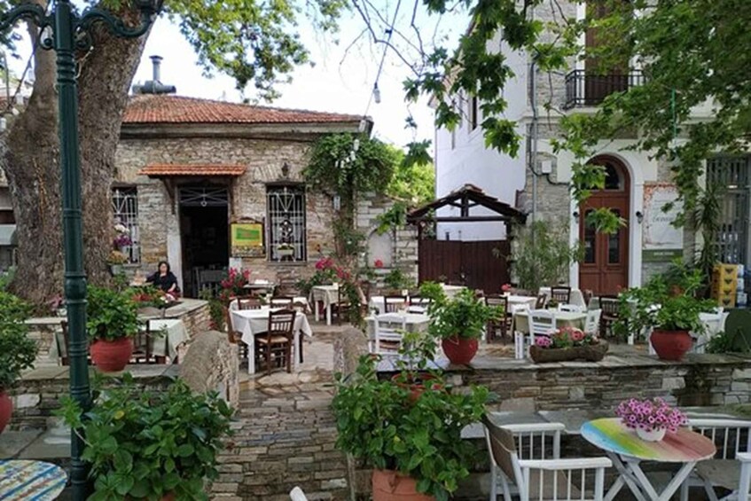 A rustic outdoor café with stone walls, potted plants, and white tables. 2