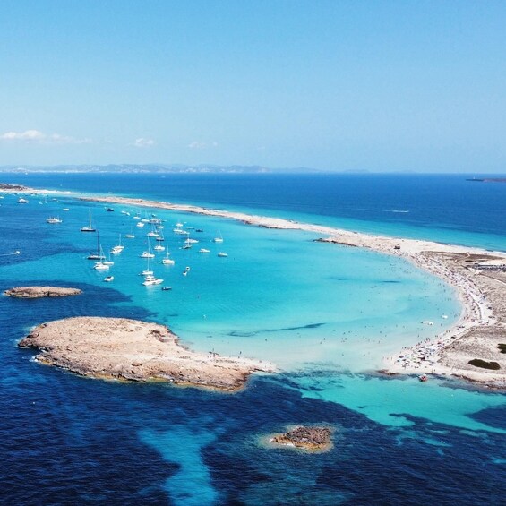 A coastal area with clear turquoise waters, numerous boats, and rocky outcrops. 1