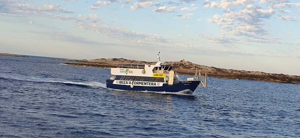 A boat named 'IBIZA=FORMENTERA' on the water with a rocky shoreline in the background. 3