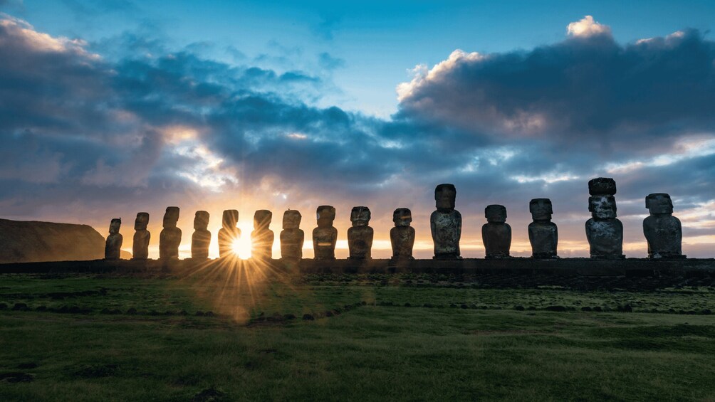 Une rangée de statues Moaï sur l’île de Pâques, avec le soleil couchant en arrière-plan. 1