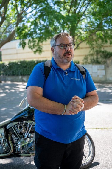 A man in a blue polo shirt standing next to a motorcycle. 2