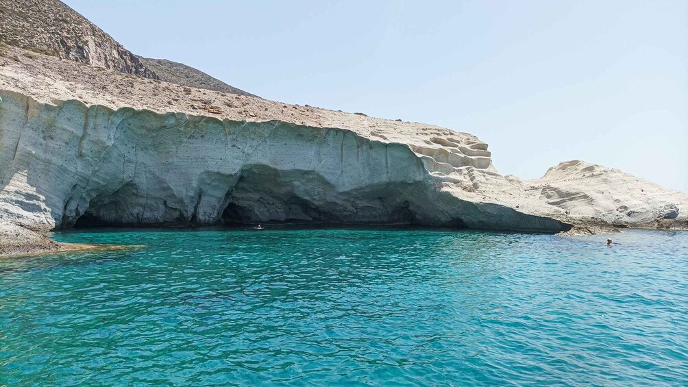 Mar azul cristalina con un acantilado rocoso y la entrada a una cueva. 5