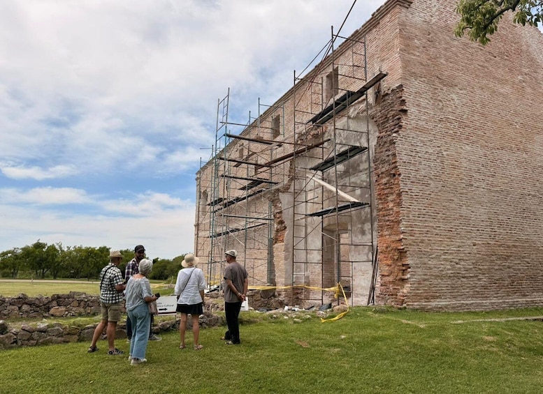 Un bâtiment en briques en construction, entouré d’échafaudages, de pelouses et d’arbres. 1