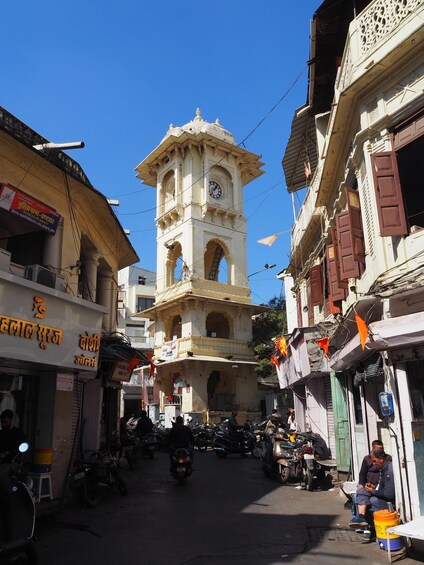 A street with a clock tower, shops, and motorcycles. 5