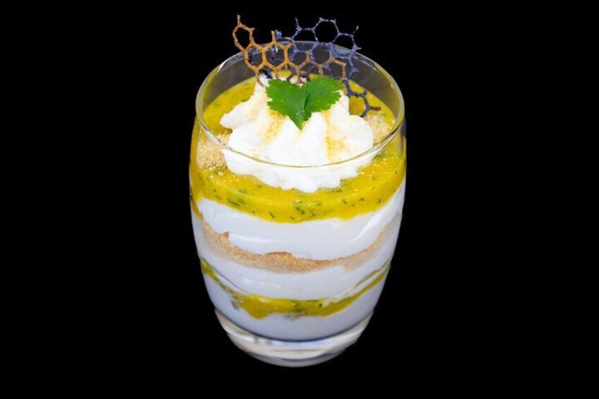 Un dessert composto da strati, servito in un bicchiere con panna montata e decorazione. 4