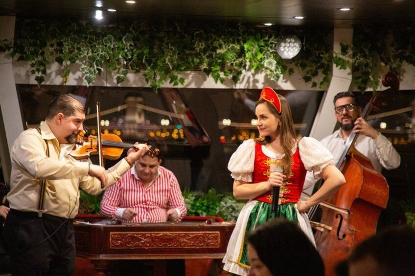 Un gruppo di musicisti che si esibisce in una sala con uno sfondo decorativo. 1