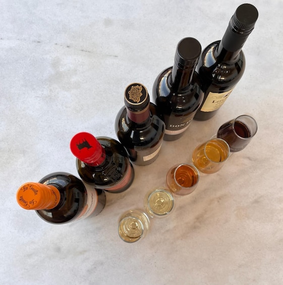 Plusieurs bouteilles de spiritueux et des verres contenant différents liquides de couleurs variées. 5