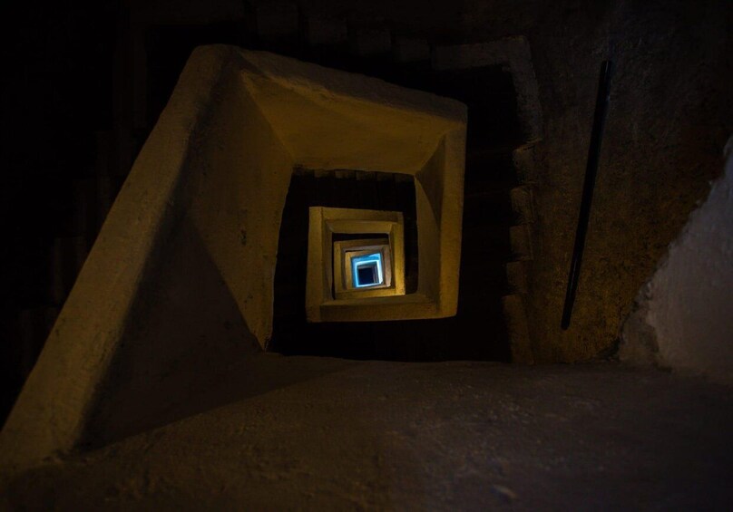 A dimly lit stairwell with a small window at the top. 3