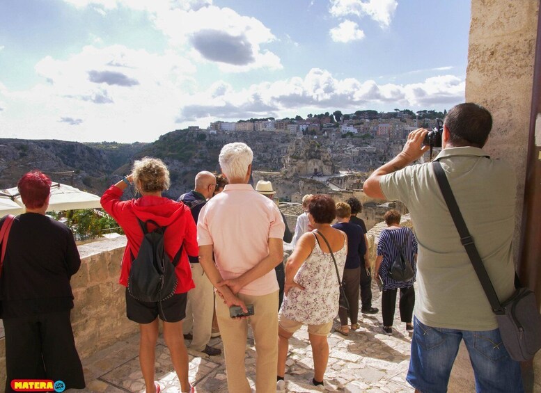 A group of people standing on a stone platform overlooking a city with buildings on a hillside. 4
