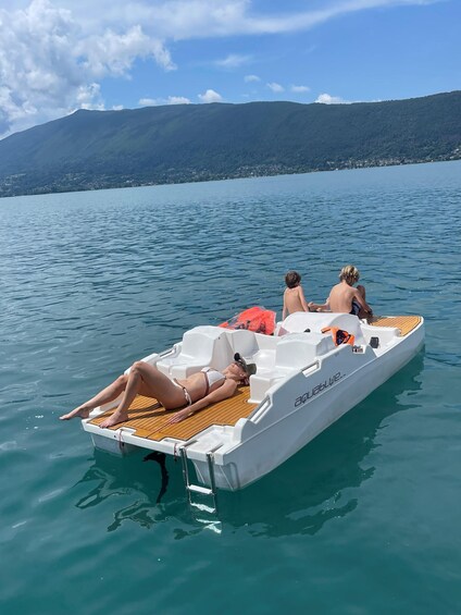 A small white boat on calm water with people relaxing on it. 3