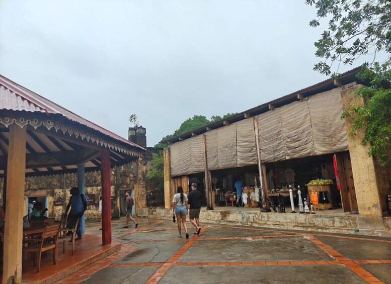 A courtyard with a covered seating area, a building with a tarp-covered entrance, and a person walking. 3