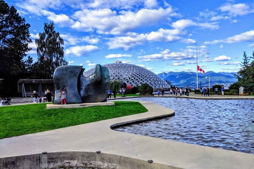 A sculpture of an elephant in a park with a body of water and mountains in the background. 4
