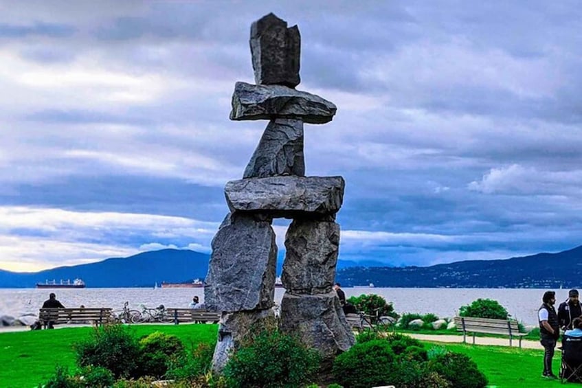 A totem pole in a park with a lake and mountains in the background. 5