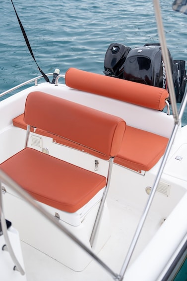 A boat's interior with orange cushioned seating and a white hull. 3