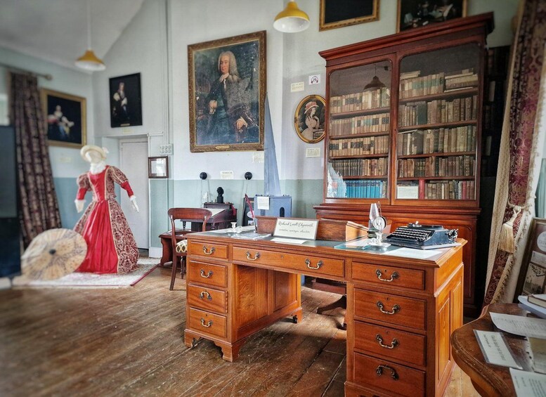Una sala de estudio antigua con un escritorio de madera, una gran estantería y un maniquí vestido de rojo. 5