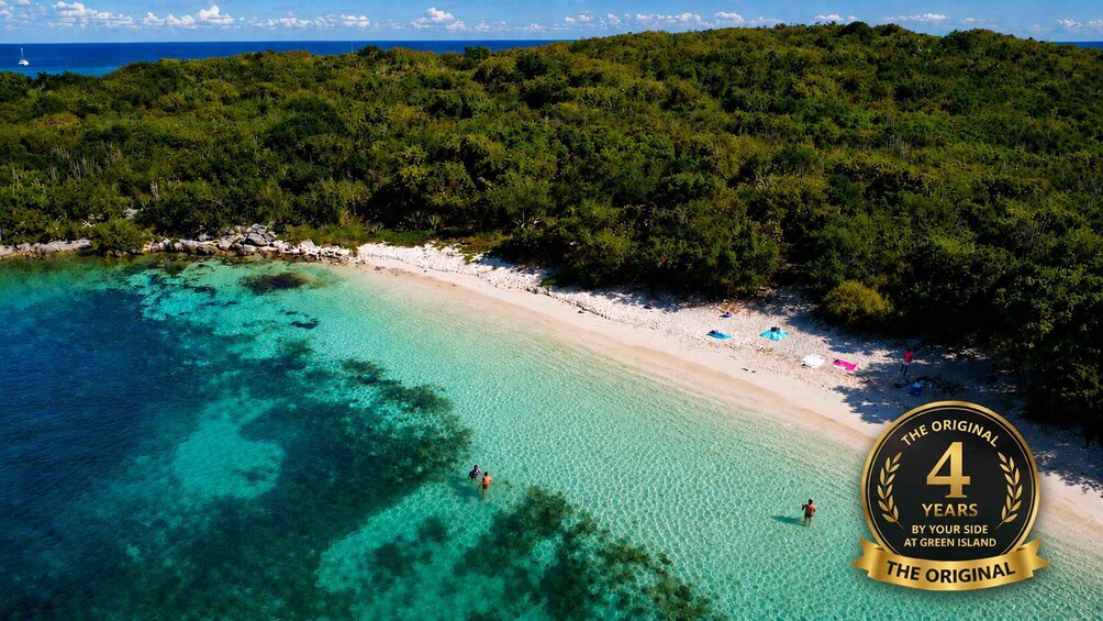 A beach with clear turquoise water, white sand, and lush green vegetation. 1