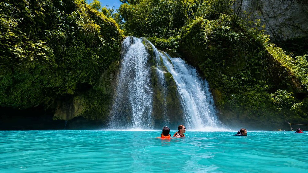 A waterfall cascading into turquoise water surrounded by lush greenery. 5