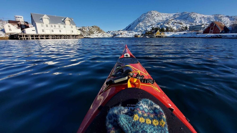 A red kayak on calm water with a snowy mountain and buildings in the background. 2