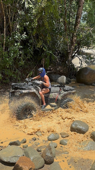 Une personne conduit un quad dans une zone boueuse, parsemée de rochers et d’arbres. 4