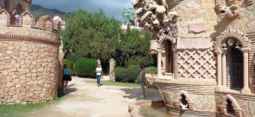 A stone pathway leading to a historic building with intricate carvings and a fountain. 2
