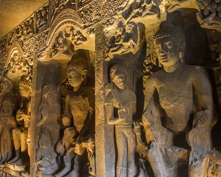 A series of stone statues in a cave, depicting various figures in traditional attire. 4
