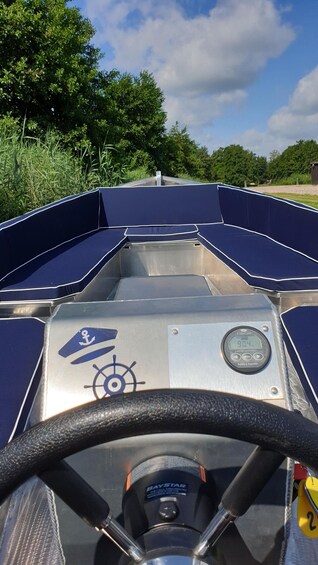 A boat's interior with a steering wheel, a digital display, and a battery monitor. 5
