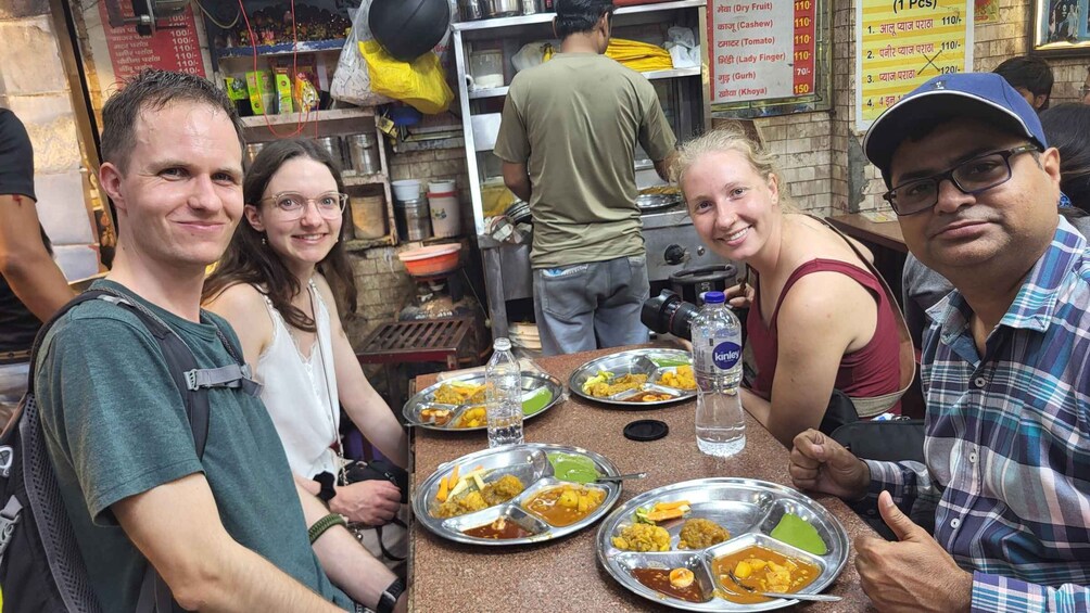 A group of people dining at a restaurant with metal plates of food. 1