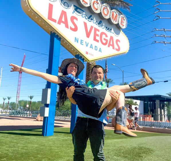 A person holding another person in front of the Las Vegas sign. 4