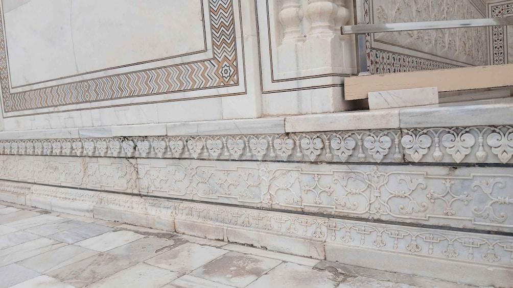 A detailed architectural wall with intricate carvings and a patterned border. 2