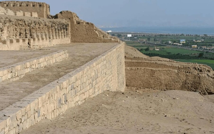 Ancient ruins with stepped terraces and a distant view of a modern cityscape. 3