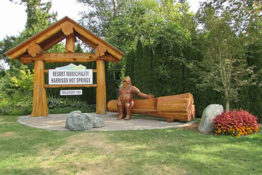 A wooden sign with 'Resort Municipality Harrison Hot Springs' and a welcome message. 2