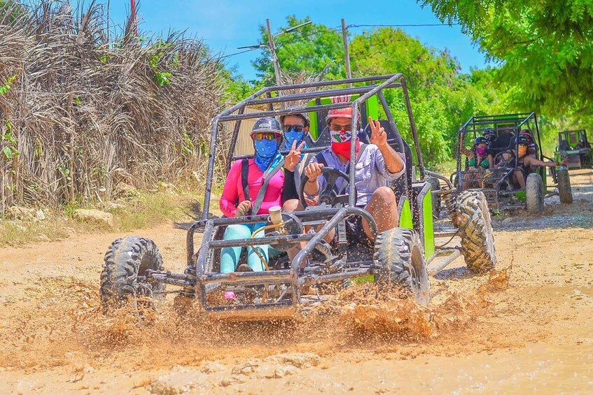 People in a vehicle driving through a muddy area. 2