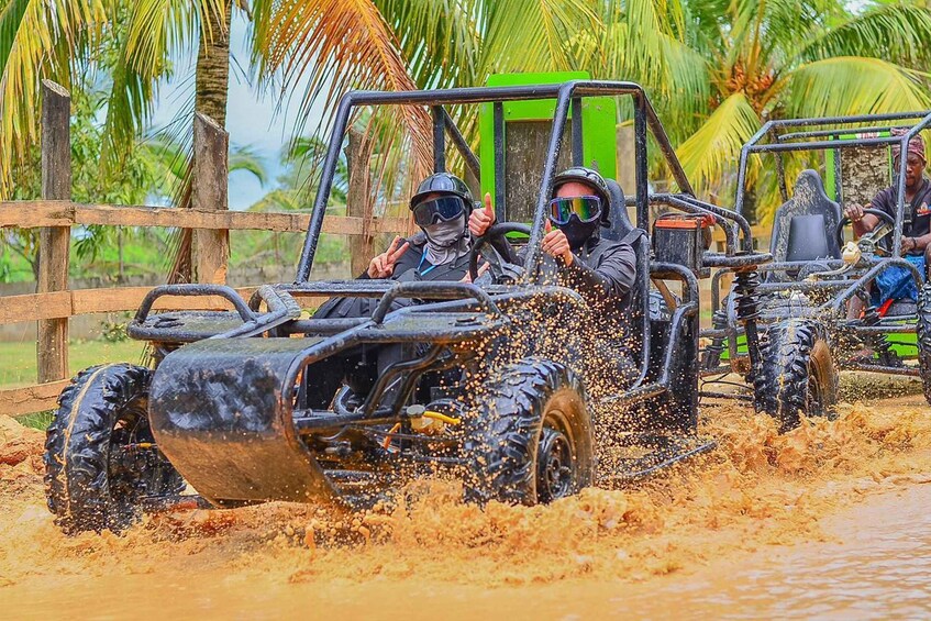 Off-road vehicles driving through a muddy area with palm trees in the background. 3