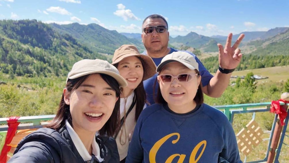 Een groep mensen maakt een selfie, met een bergachtig landschap op de achtergrond. 2