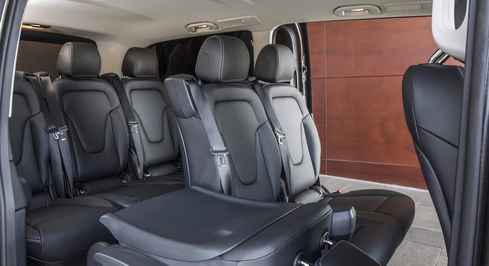 Interior de vehículo con asientos de cuero negro, una consola central y un panel de madera lateral. 5