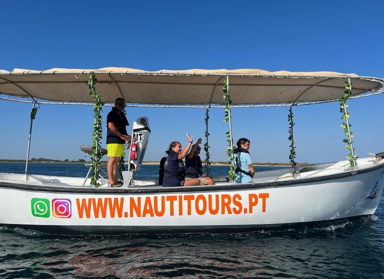A boat with a canopy and passengers, water, and a distant shoreline. 1