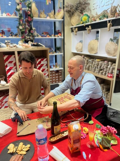 Two men working on a craft project with tools and materials on a table. 1