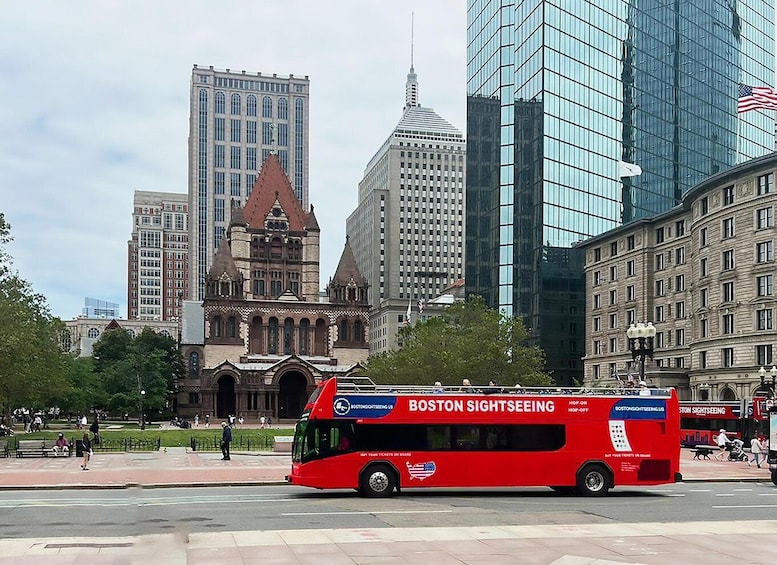 A red Boston Sightseeing bus in a city with historic buildings and modern skyscrapers. 1