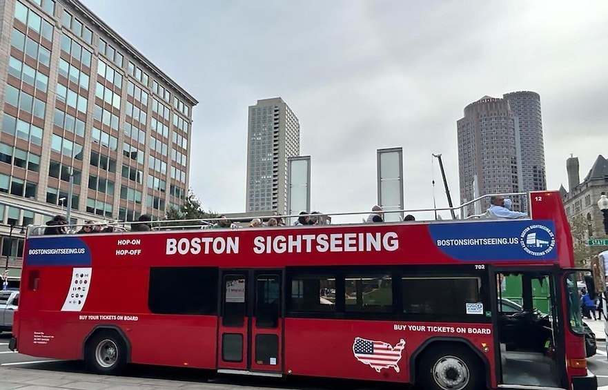 A red Boston Sightseeing bus with "BOSTONSIGHTSEEING.US" and "BUY YOUR TICKETS ON BOARD" on its side. 2