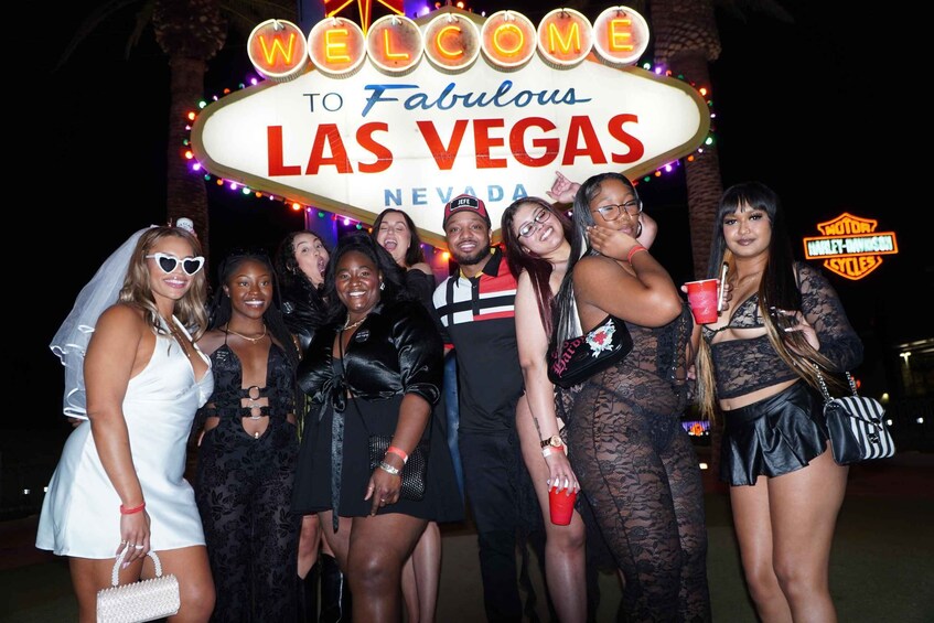 A group of people in front of a 'Welcome to Fabulous Las Vegas Nevada' sign. 1