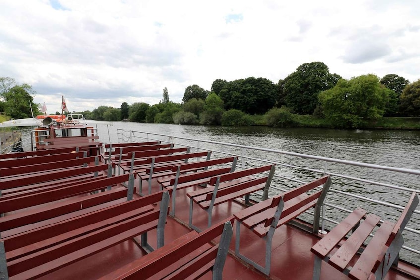 A river with a boat docked on the left, featuring red benches along the side. 4