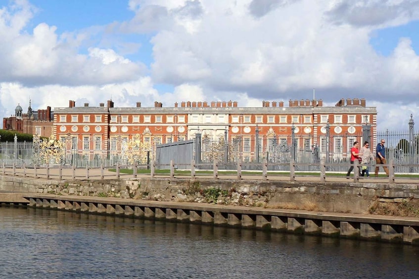 A large red brick building with a central courtyard, surrounded by a stone wall and a metal fence. 1