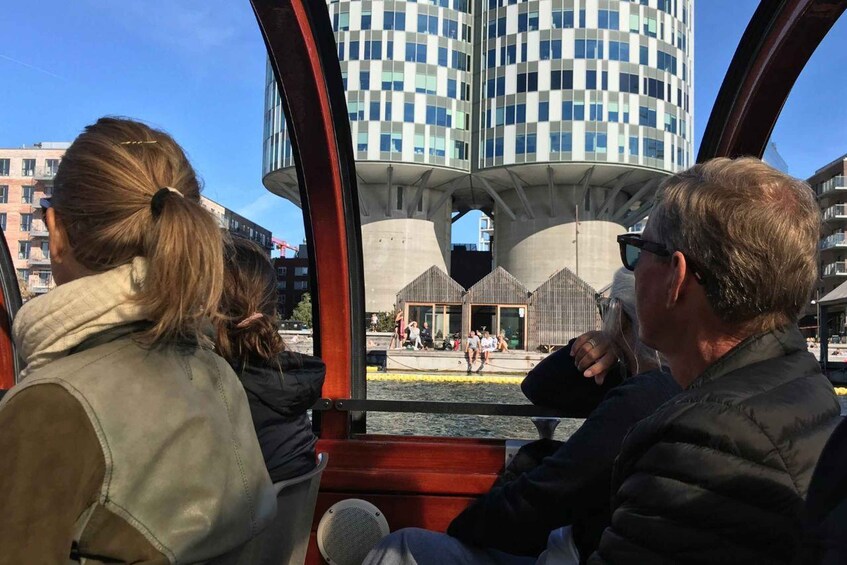 A boat with two passengers looking at a modern building with a checkered facade. 5