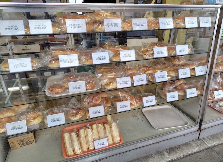 A bakery display case with various bread items labeled with prices. 3