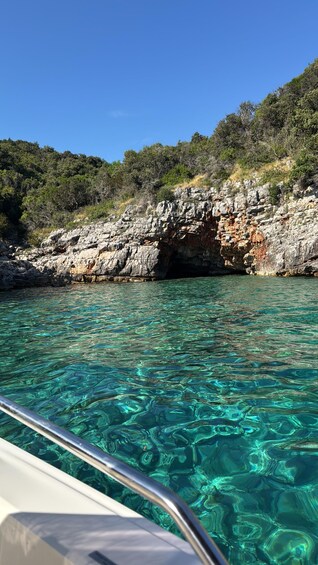 A boat near a rocky coastline with clear turquoise water. 2