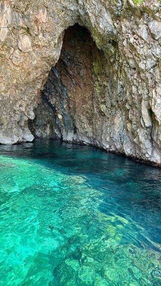 A rocky cave entrance with clear turquoise water. 3