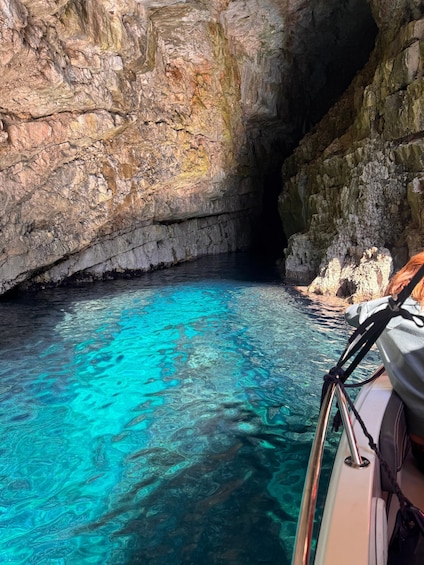 A boat in a clear blue cave with rocky walls. 5